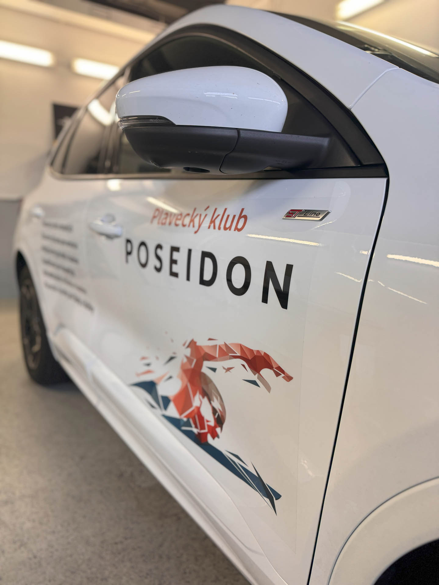 Polepy aut: biely Ford Kuga s logom Plaveckého klubu Poseidon na bočných dverách
